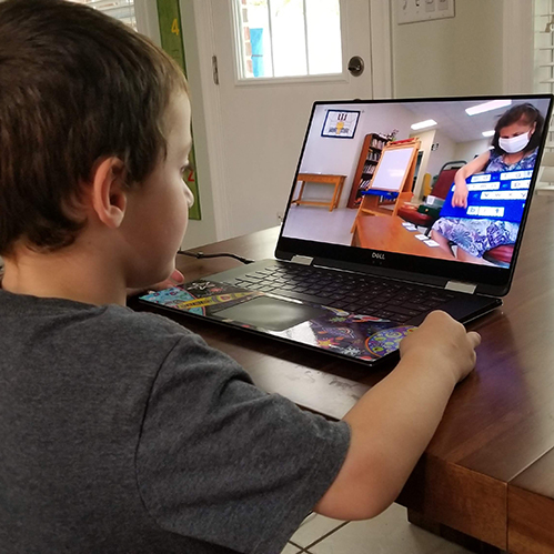 Child watching virtual classes on computer.