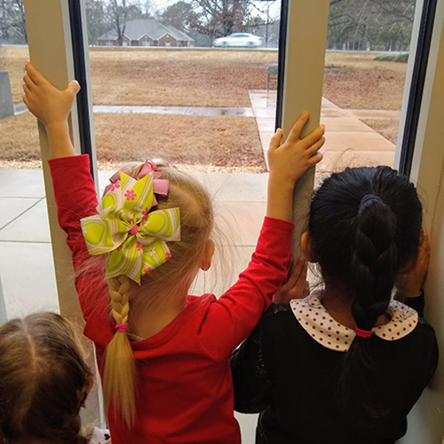 Children looking out school window.